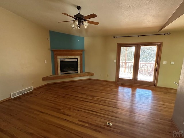 unfurnished living room featuring visible vents, a fireplace, wood finished floors, and a ceiling fan