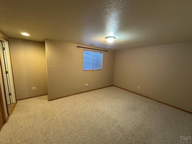 empty room with visible vents, light colored carpet, baseboards, and a textured ceiling