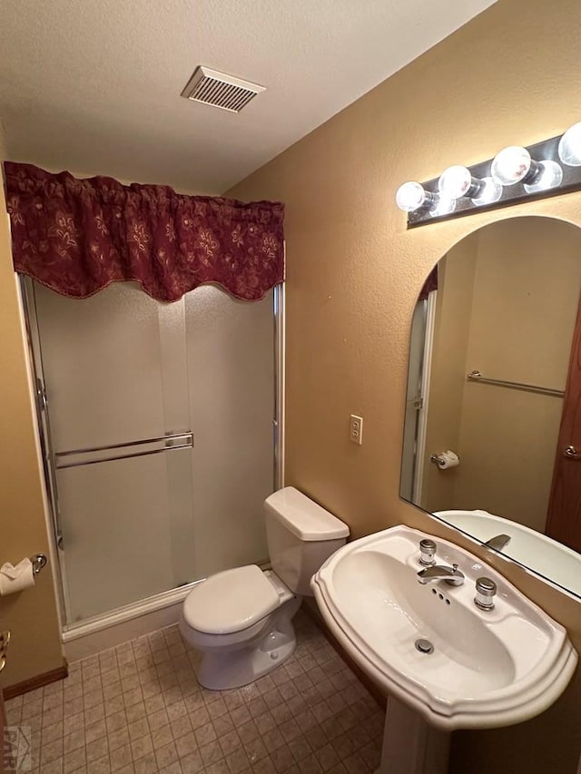 full bath featuring visible vents, toilet, a stall shower, a sink, and a textured ceiling