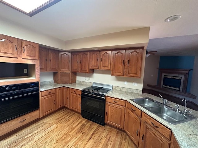 kitchen with black appliances, light wood-style flooring, a sink, light countertops, and ceiling fan