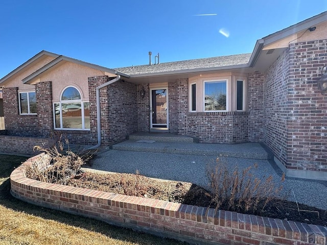 exterior space with brick siding and a patio area