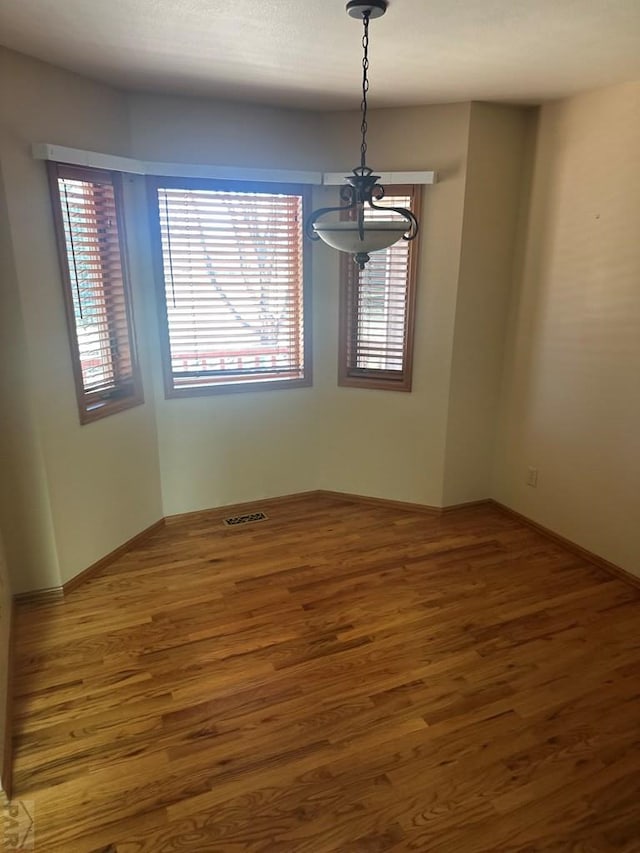 spare room with wood finished floors and visible vents