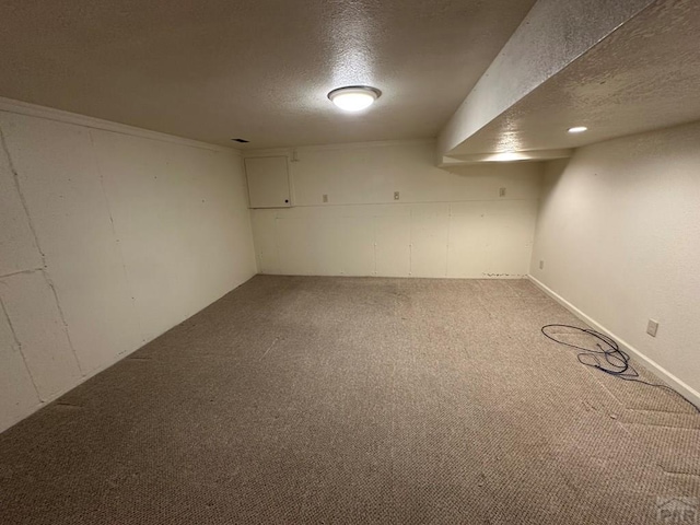 finished basement with light colored carpet and a textured ceiling