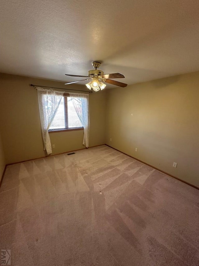 unfurnished room with visible vents, a ceiling fan, a textured ceiling, baseboards, and light colored carpet