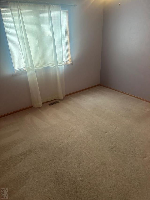 unfurnished room with light colored carpet, visible vents, and baseboards