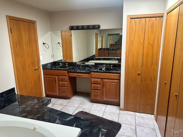 bathroom with tile patterned flooring, double vanity, a tub, and a sink