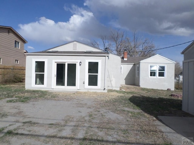 3023 Cascade Ave, Pueblo, CO 81008 - back of house with a chimney, stucco siding, and fence