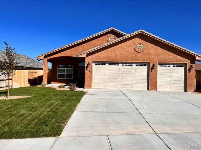 ranch-style house featuring a garage, fence, a front lawn, and stucco siding