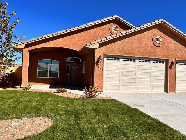 ranch-style home featuring a garage, concrete driveway, a front lawn, and stucco siding