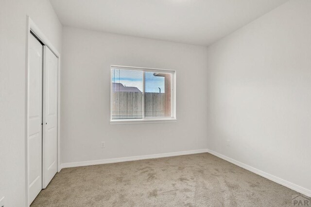 unfurnished bedroom with light carpet, baseboards, and a closet