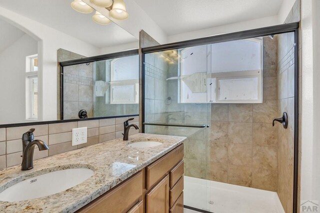 bathroom featuring double vanity, a stall shower, a sink, and backsplash