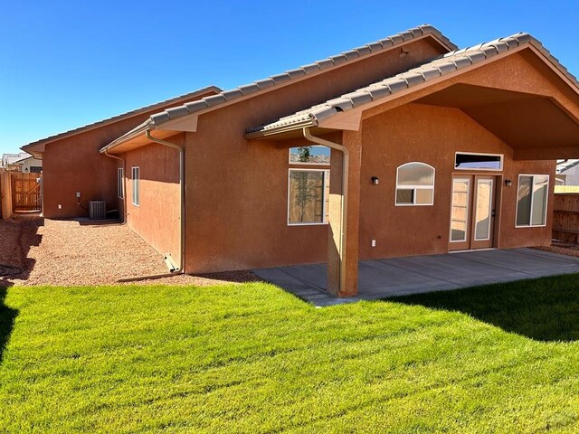 back of house featuring fence, cooling unit, a yard, a patio area, and stucco siding