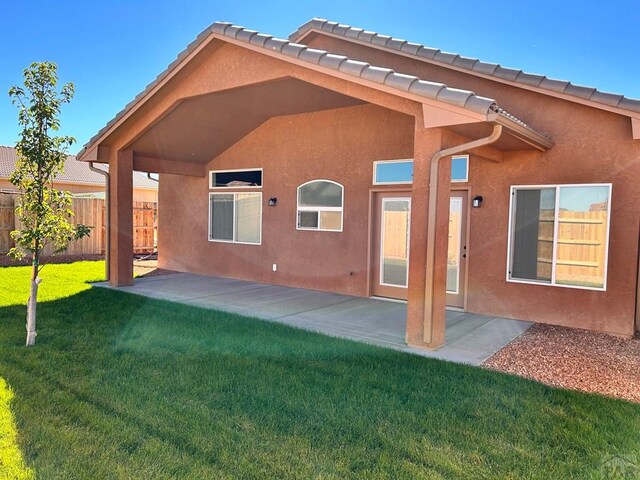 back of house featuring a yard, a patio, and stucco siding