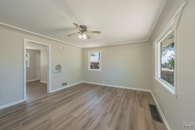 spare room with baseboards, visible vents, and wood finished floors