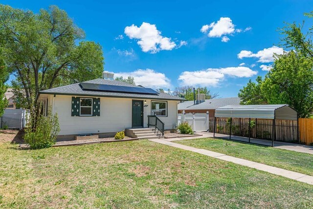 ranch-style house with a detached carport, fence, driveway, and a front lawn