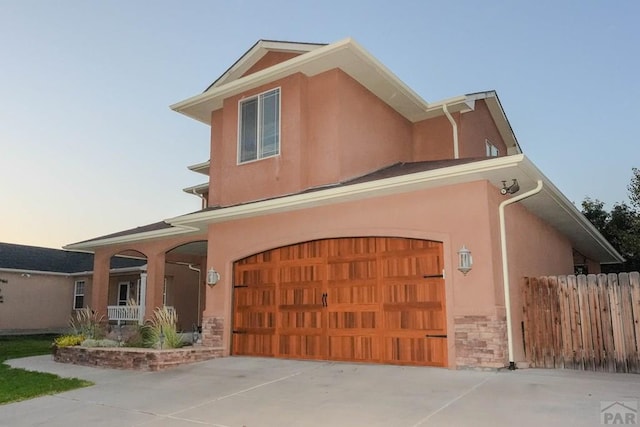 view of front facade with stone siding, concrete driveway, and stucco siding