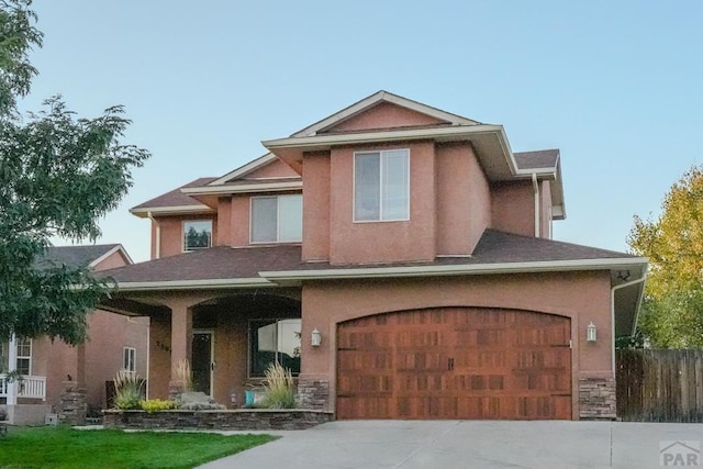 view of front of property featuring stone siding, fence, concrete driveway, and stucco siding