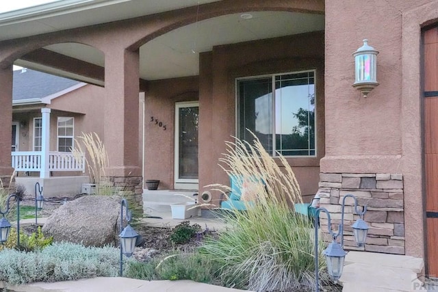 view of exterior entry with a porch and stucco siding