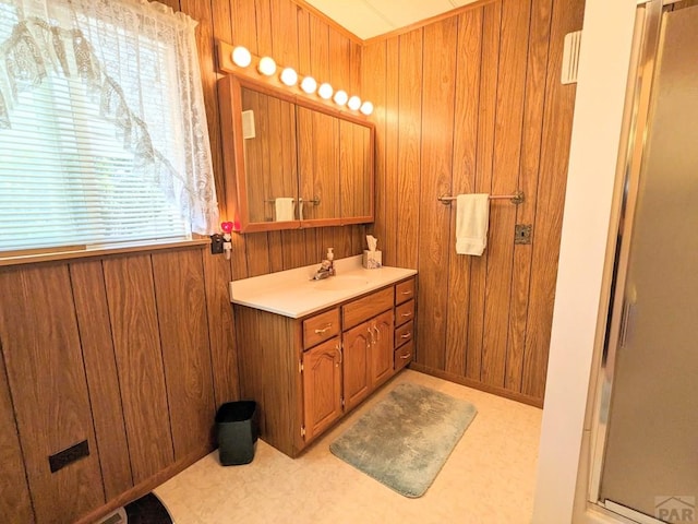 bathroom with a wealth of natural light, a shower stall, wooden walls, and vanity