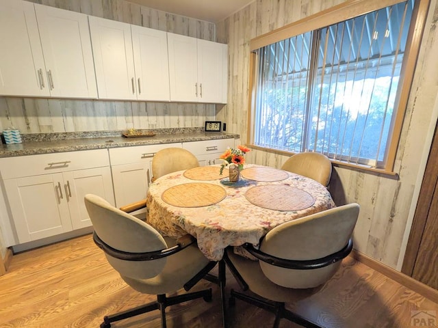 dining room featuring light wood-type flooring and wallpapered walls