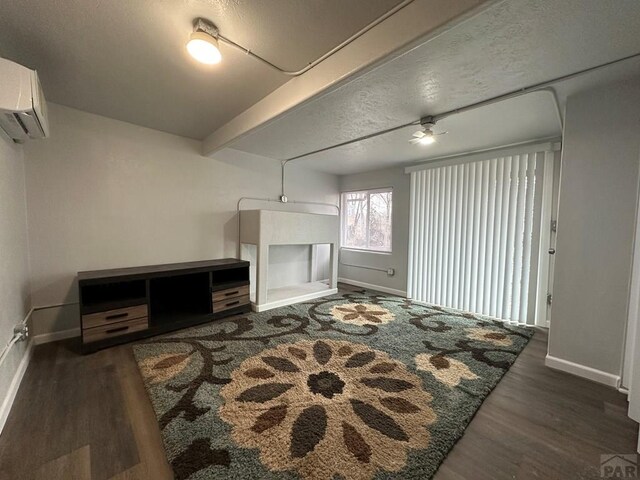 living area with a wall unit AC, dark wood finished floors, beam ceiling, and baseboards