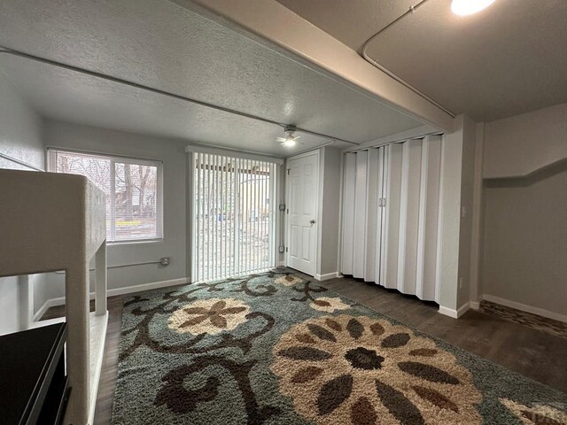 foyer featuring a textured ceiling, baseboards, and dark wood-style flooring