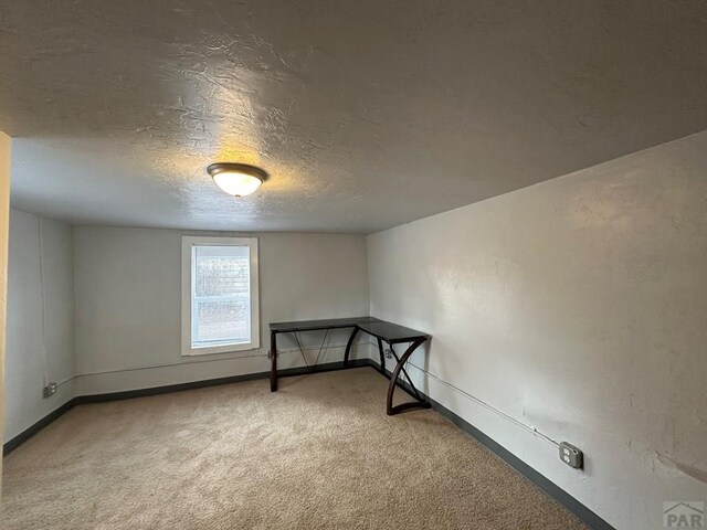 carpeted spare room with a textured ceiling and baseboards