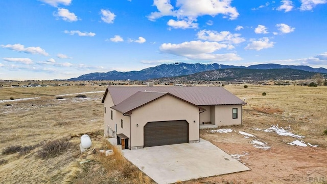 view of front of property with metal roof, a mountain view, a garage, driveway, and stucco siding