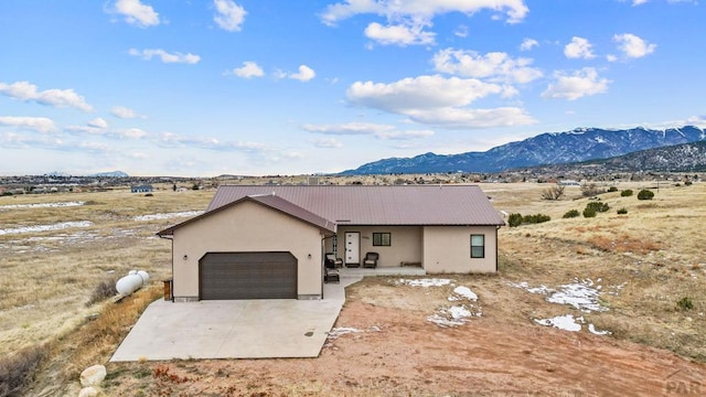 view of front of house with a garage, metal roof, a mountain view, and concrete driveway