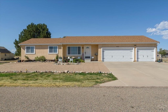 ranch-style home with driveway, an attached garage, and stucco siding