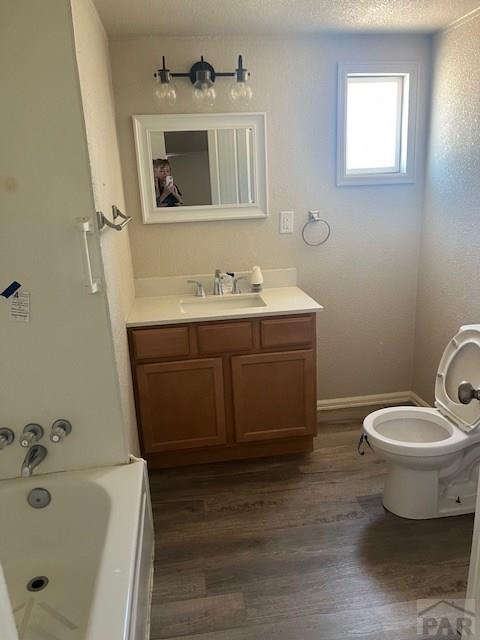 full bath featuring a textured ceiling, toilet, wood finished floors, and vanity