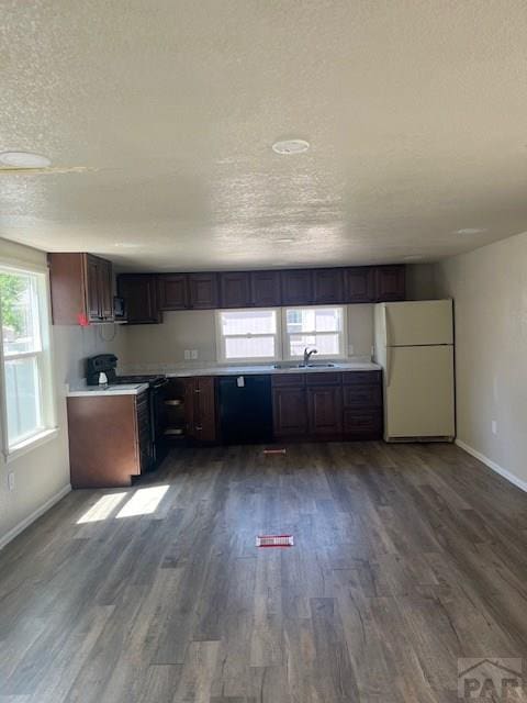 kitchen featuring dark brown cabinetry, stove, wood finished floors, freestanding refrigerator, and light countertops