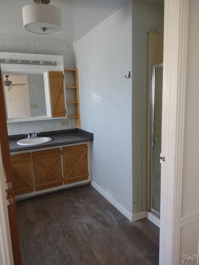 bathroom with a shower stall, wood finished floors, vanity, and baseboards