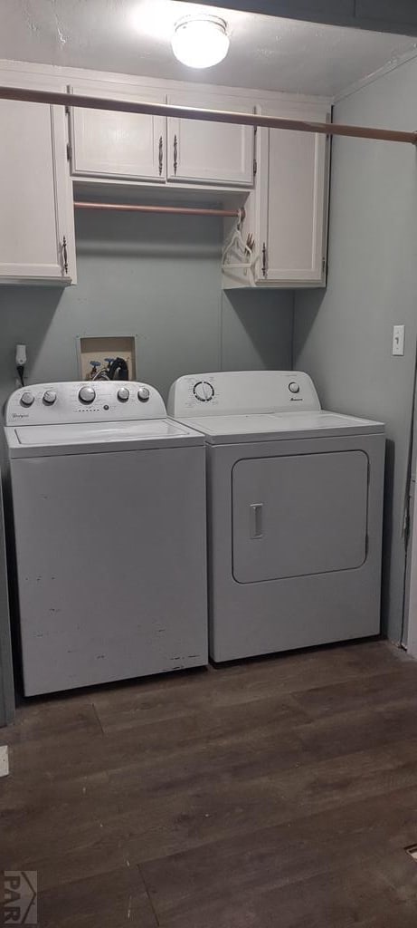 clothes washing area with dark wood-style flooring, cabinet space, and washing machine and clothes dryer