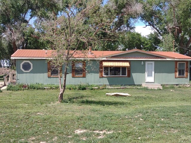 view of front of house with metal roof and a front lawn