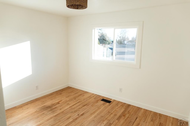 unfurnished room featuring light wood finished floors, baseboards, and visible vents