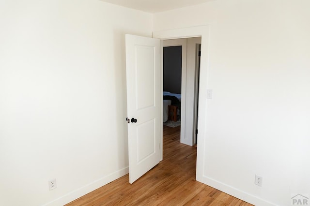 empty room featuring light wood-type flooring and baseboards