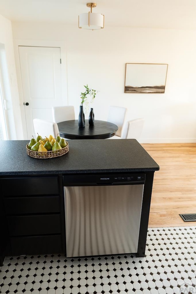 kitchen featuring baseboards, visible vents, dark countertops, light wood-style floors, and stainless steel dishwasher