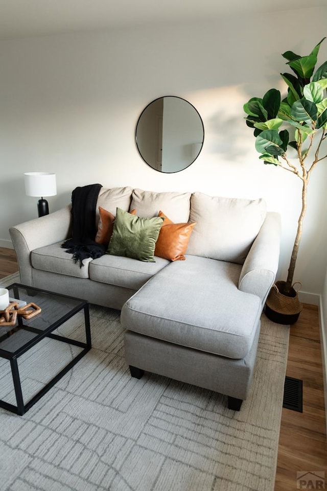 living area featuring visible vents, baseboards, and wood finished floors