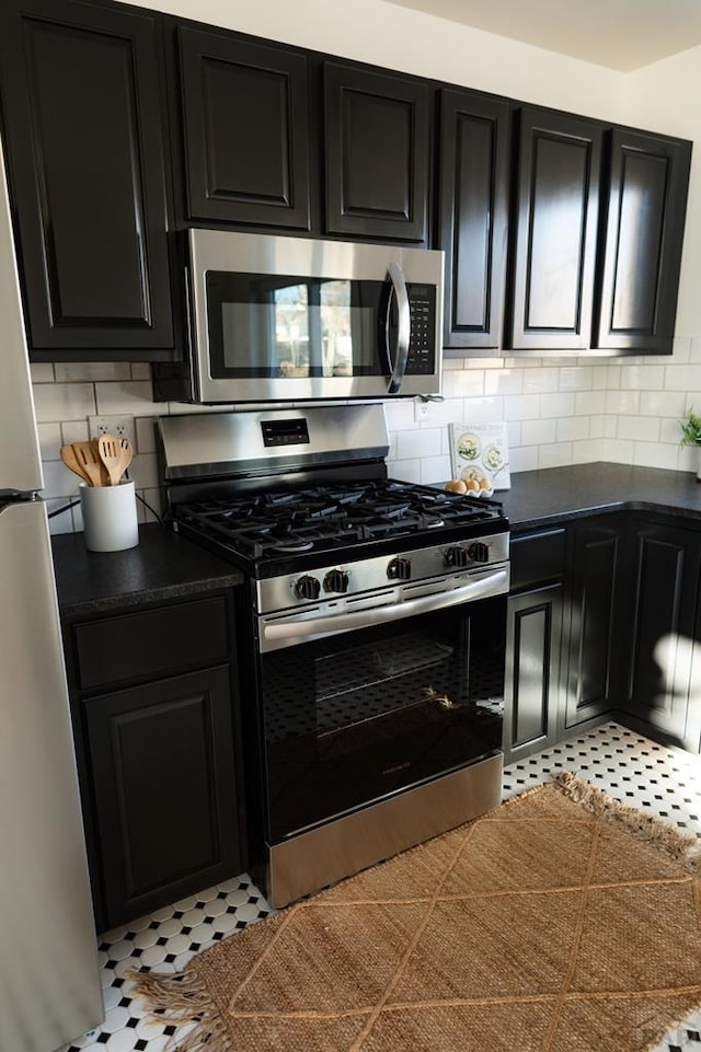 kitchen with dark countertops, decorative backsplash, stainless steel appliances, and dark cabinetry