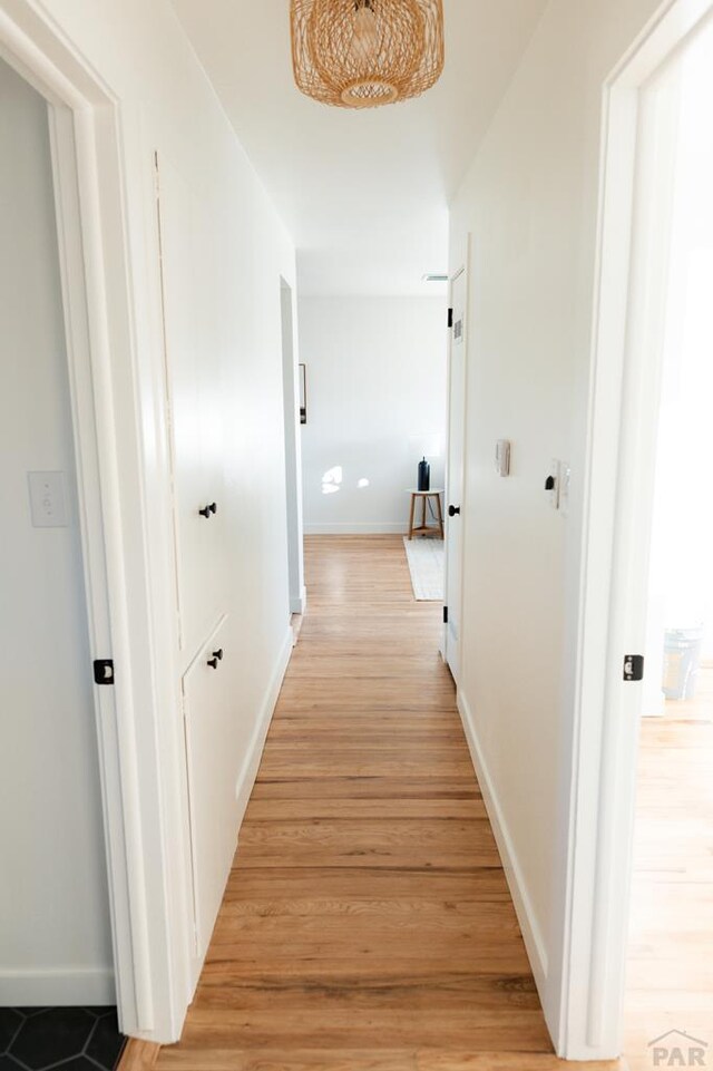 corridor with light wood-style floors and baseboards