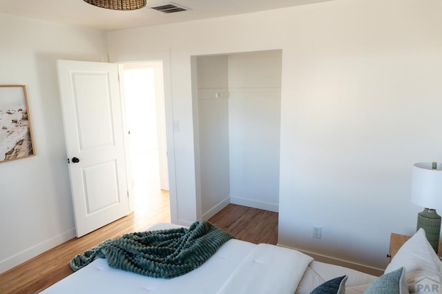 bedroom with baseboards, visible vents, and wood finished floors