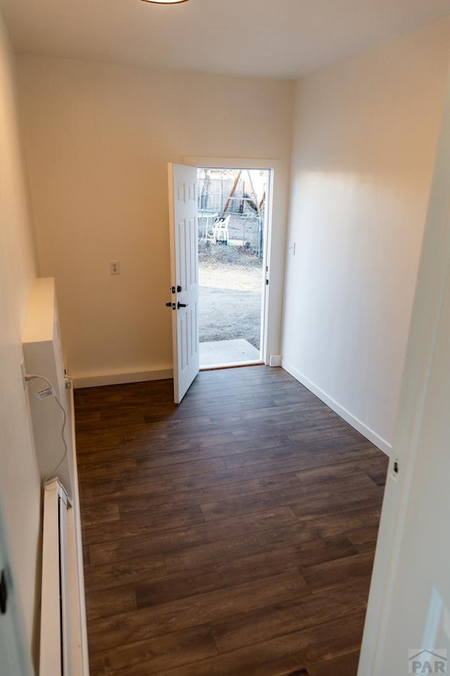 doorway featuring baseboards and dark wood-type flooring