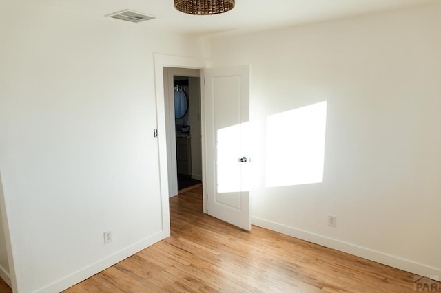 unfurnished room featuring visible vents, light wood-style flooring, and baseboards