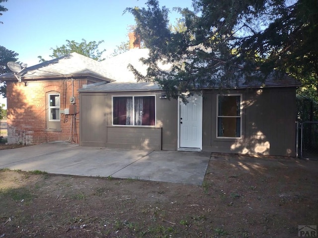 view of front of house featuring brick siding and a patio