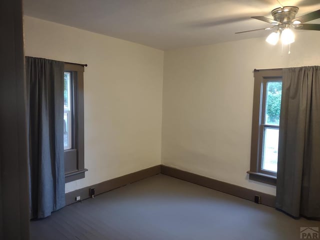 empty room with ceiling fan and baseboards