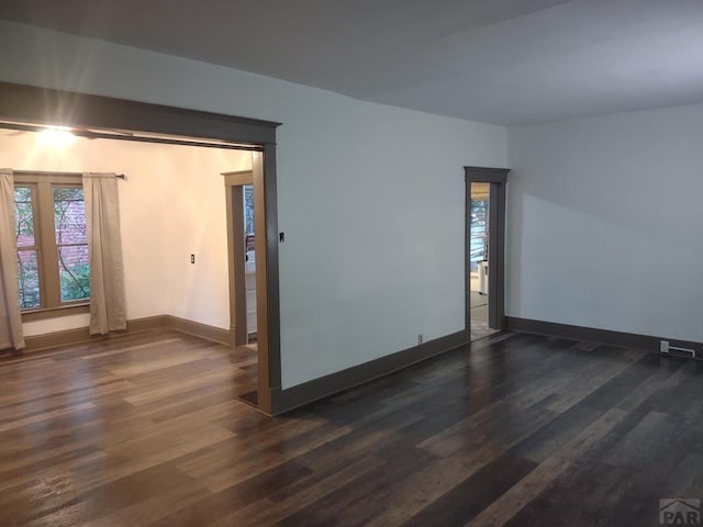 unfurnished room with dark wood-style flooring and baseboards
