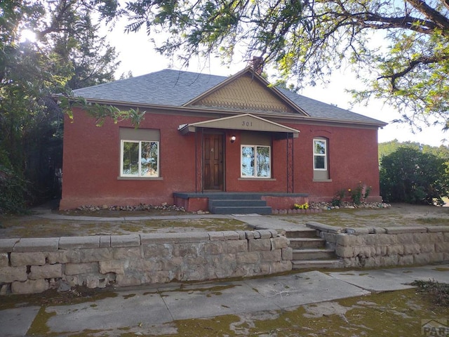 view of front of home featuring a shingled roof and stucco siding