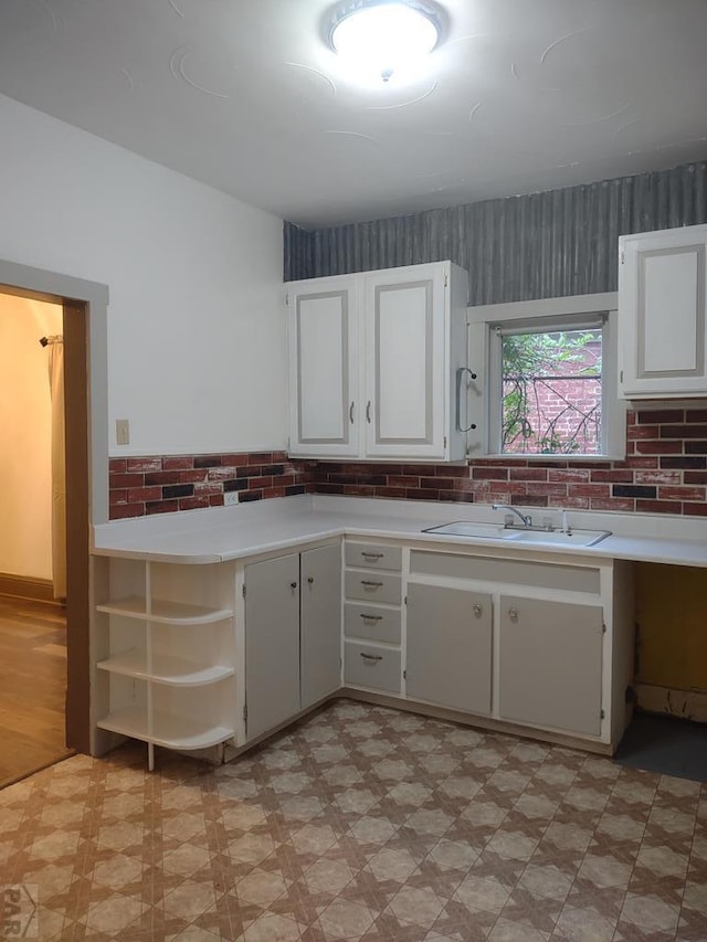 kitchen with light countertops, light floors, white cabinetry, open shelves, and a sink