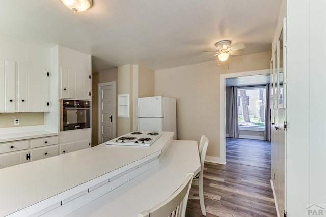 319 S Main St, La Veta, CO 81055 - kitchen featuring white appliances, a ceiling fan, white cabinets, dark wood-style floors, and light countertops